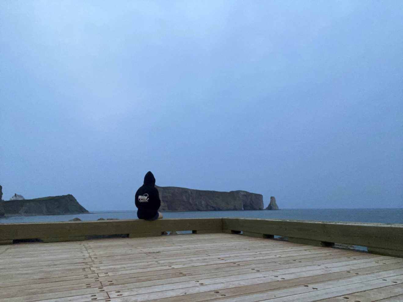 a woman sitting by the water near Rocher Percé in gaspésie