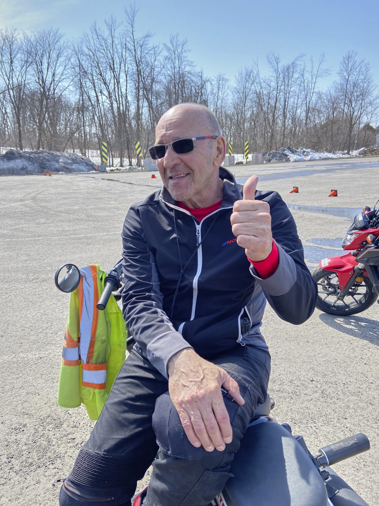 Patrick Sanchez, formateur de moto assis sur son véhicule montrant un pouce en l'air