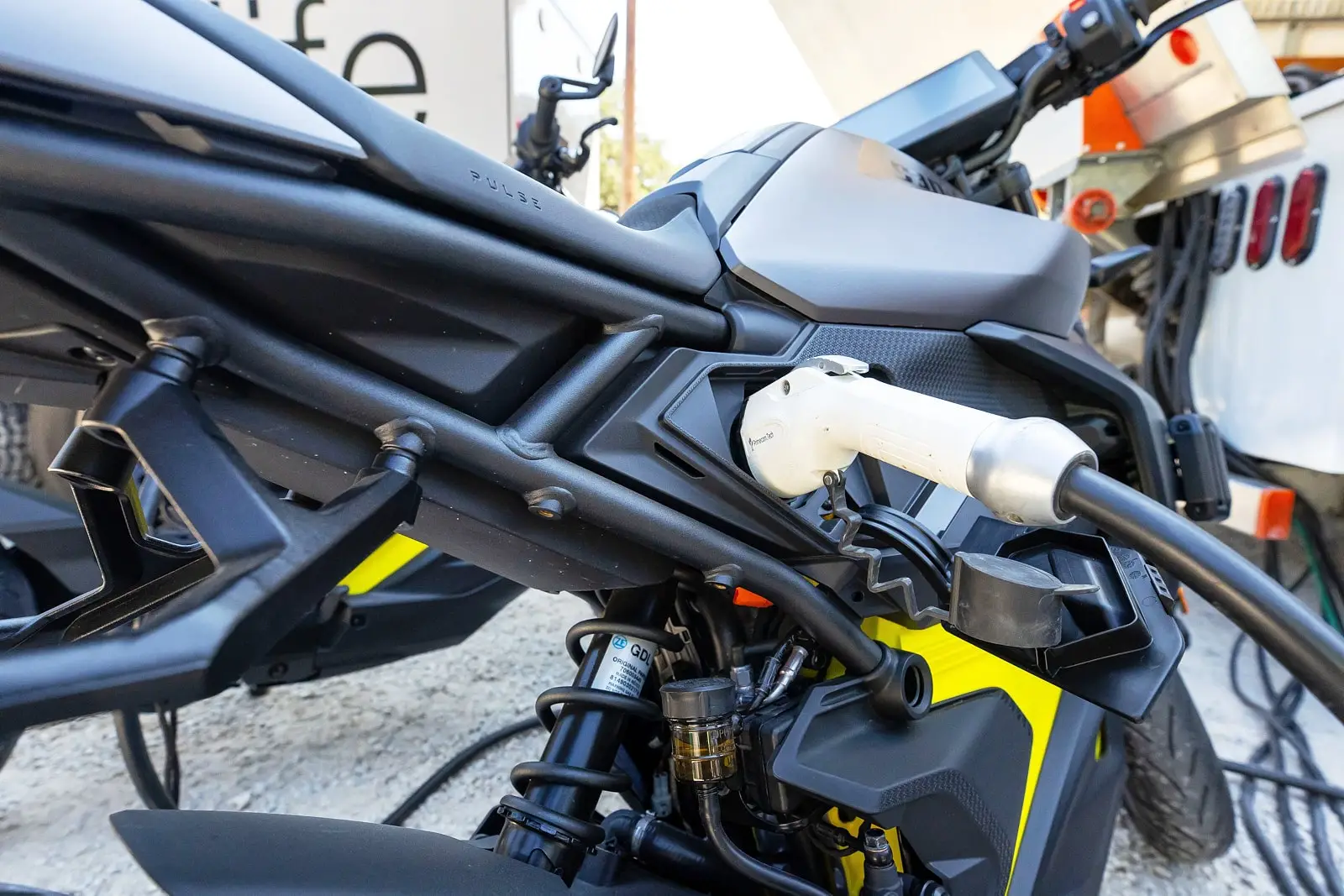 Can-Am Pulse electric motorcycle being charged, with the charging cable plugged into the side of the vehicle.