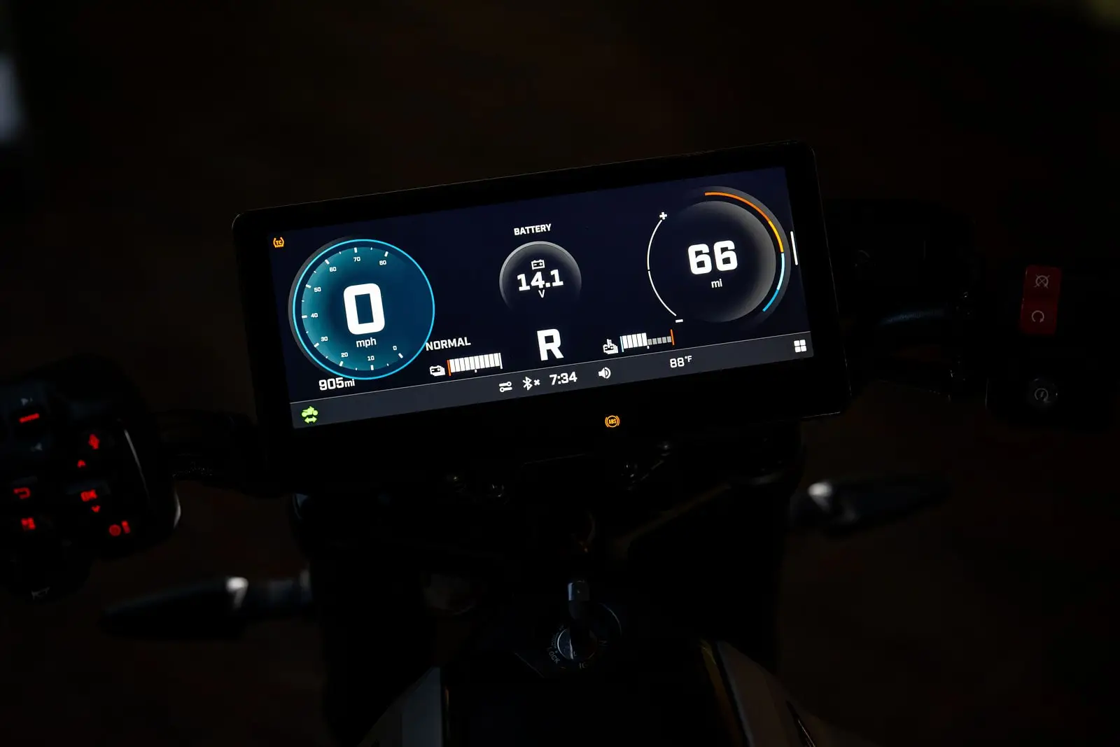 Digital display on a motorcycle showing speed, battery level, driving mode, remaining range, and outside temperature.