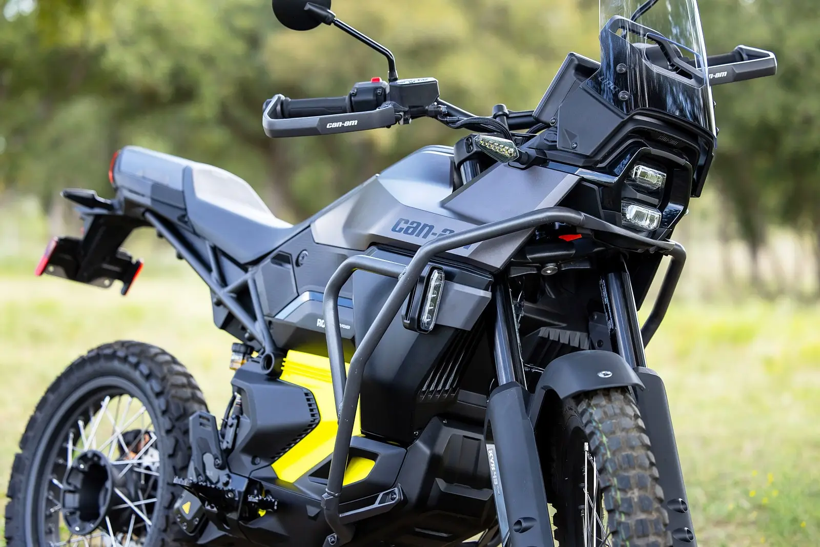 Close-up of a Can-Am electric motorcycle with a reinforced bumper, bright yellow details, and off-road tires.