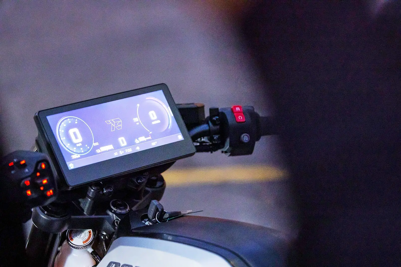 Close-up of a Can-Am motorcycle’s digital display, showing speed and battery information, with illuminated handlebar controls.