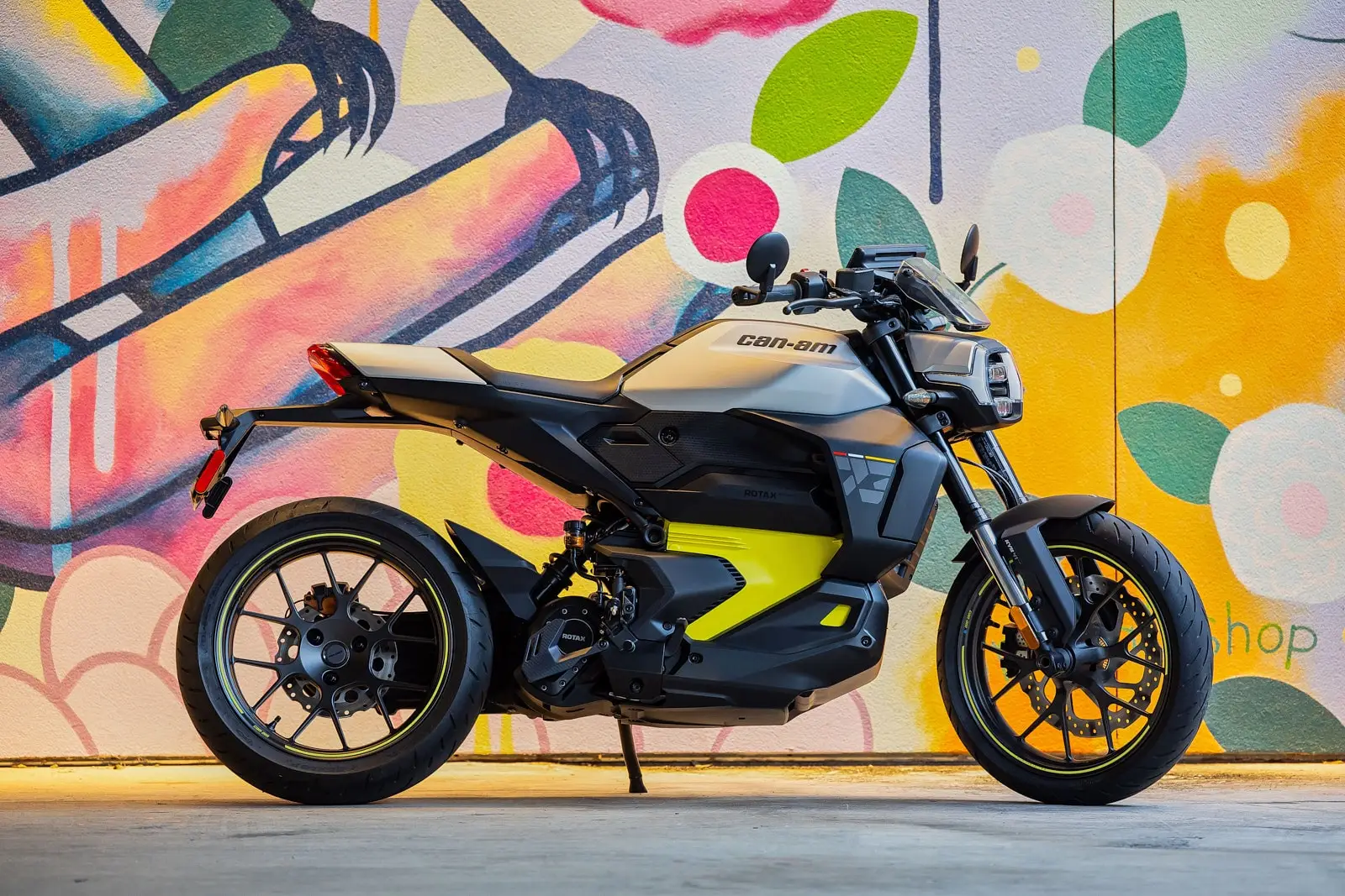 La moto électrique Can-Am Pulse est garée devant un mur coloré avec une fresque artistique.